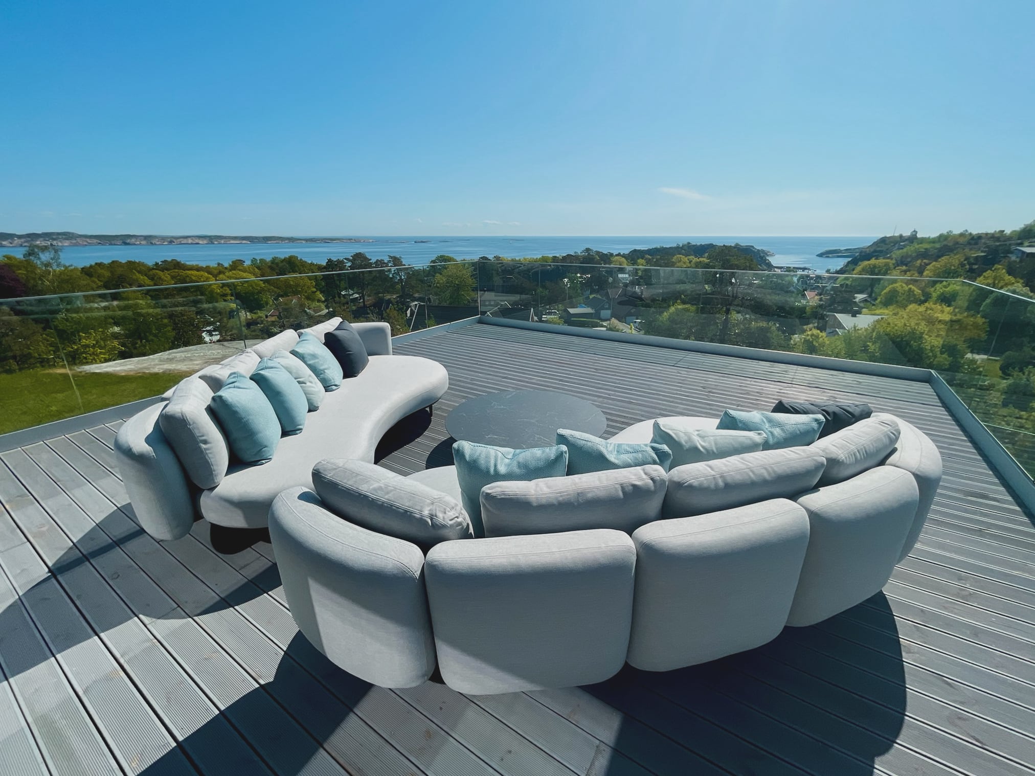 Takterrasse med avrundede sofaer og utsyn over skjærgården